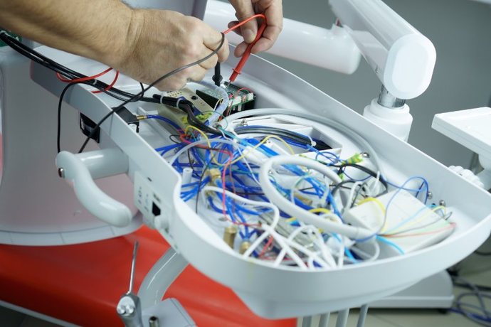 Technician testing the wiring inside a dental chair